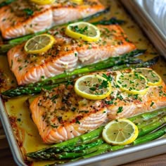 salmon and asparagus on a baking sheet with lemons, parsley and seasoning