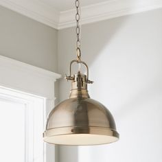 an antique style pendant light hanging from the ceiling in a room with white walls and windows