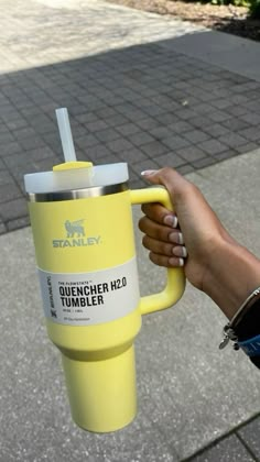 a person holding a yellow cup with a straw in it