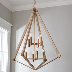 a wooden chandelier hanging from the ceiling in a room with white walls and windows