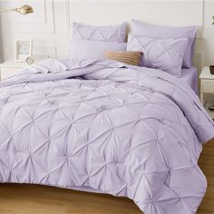 a bed with purple comforter and pillows on it