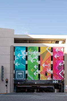 a large building with colorful banners on it's side and an arrow sign above the door