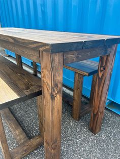 a wooden table and bench sitting next to a blue container