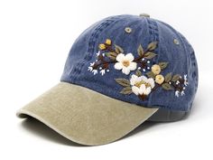 a blue hat with white flowers on the front and tan brimmed side panels