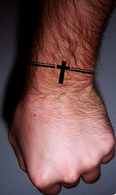 a man's wrist with a cross tattoo on it