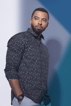 a man with a beard standing in front of a blue and white background