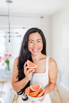 a woman holding up slices of grapefruit in her hand and smiling at the camera