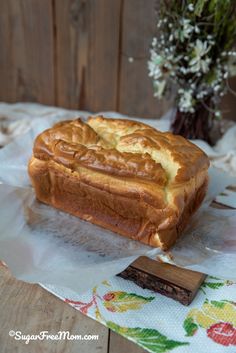 a loaf of bread sitting on top of a table next to a vase with flowers