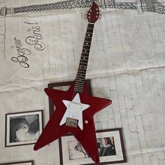 a red and white guitar sitting on top of a table next to pictures with writing