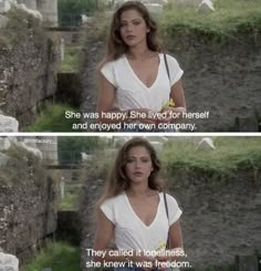 a woman in white dress standing next to a stone wall with words written on it