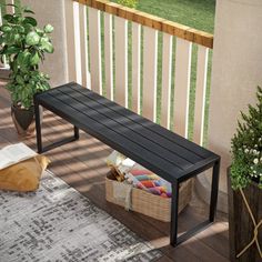 a black bench sitting on top of a wooden floor next to a potted plant