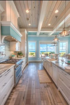 a large kitchen with wooden floors and blue walls, along with white cabinets and counter tops