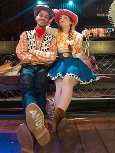 a man and woman dressed up as cowboys sitting on a bench in front of a stage