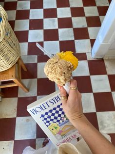 a person holding an ice cream sundae with toppings on it in front of a checkered floor