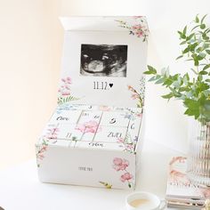 an empty box sitting on top of a table next to a vase with flowers in it