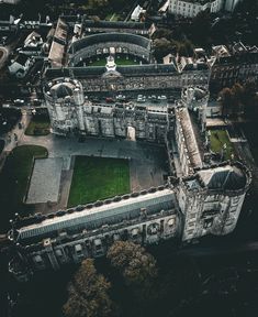 an aerial view of a large building in the middle of a city with lots of green grass