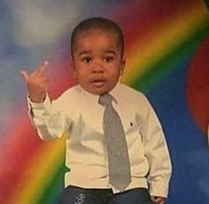 a young boy wearing a tie and dress shirt posing for a photo in front of a rainbow backdrop