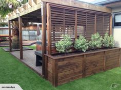 a wooden deck with plants on it and a grill in the back ground next to it