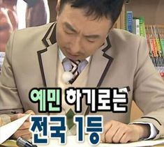 a man sitting at a desk writing in front of a book shelf with books on it