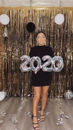 a woman standing in front of balloons and streamers with the number 20 on it