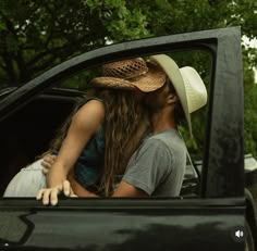 a man and woman kissing in the back of a pick up truck with trees in the background