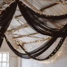 the ceiling is decorated with lights and black draping for an elegant wedding reception