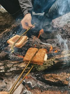 someone cooking food on sticks over an open fire