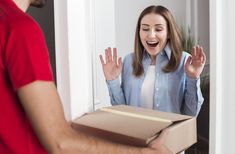 a woman holding a box with her hands in the air and an excited man standing next to her