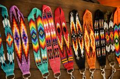 colorful bracelets are hanging on the wall in a row, with metal hooks attached to them