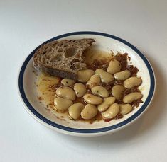 a white bowl filled with food on top of a table next to a slice of bread