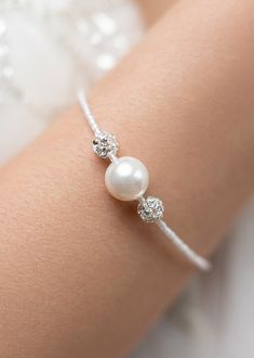 a close up of a person wearing a bracelet with pearls and diamonds on the arm