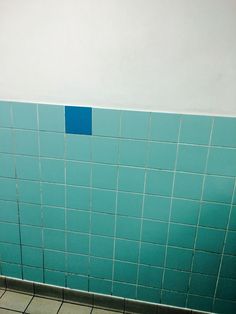 a blue tiled wall in a public restroom