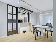 an open concept kitchen and dining area with white walls, wood floors and black framed glass doors