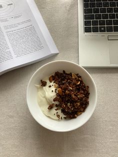 a bowl of granola and yogurt next to an open book