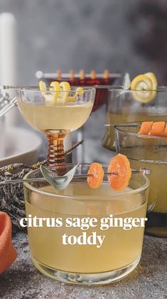 two glasses filled with liquid and orange peels on top of a table next to other drinks