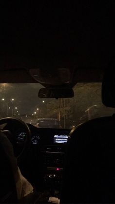 the interior of a car at night, with lights on and streetlights in the background