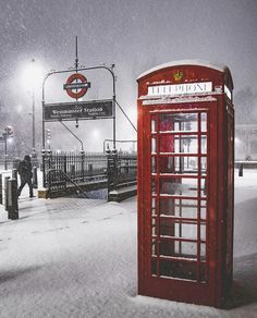 a red phone booth sitting in the snow