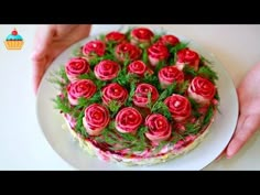 a person holding a plate with a cake on it that has red roses on it