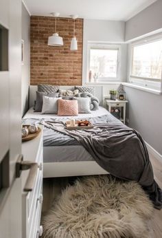 a bedroom with a brick wall and bed in the corner, rug on the floor