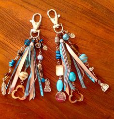 two pairs of keychains with charms attached to them on a wooden table top