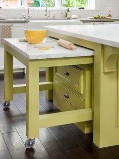 a kitchen island with a marble top and two drawers on casteors in the center