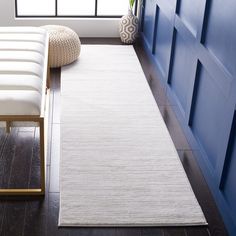 a white rug sitting on top of a hard wood floor next to a blue wall