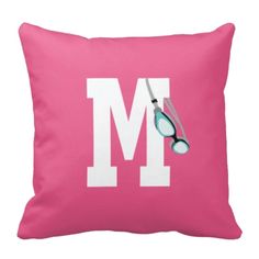 a pink pillow with a pair of scissors on it and the letter m in white