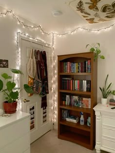 a bookshelf filled with lots of books next to a white dresser and door