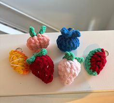 four crocheted fruits are sitting on a white surface