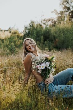 a woman sitting in the grass holding flowers