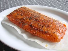 a piece of salmon on a white plate with seasoning sprinkled over it