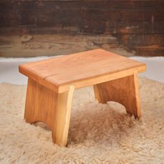 a small wooden stool sitting on top of a white rug