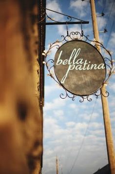 a sign that says belbatina hanging from the side of a wooden pole in front of a cloudy blue sky