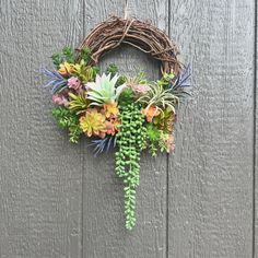 a wreath with succulents and other flowers hanging on a wall